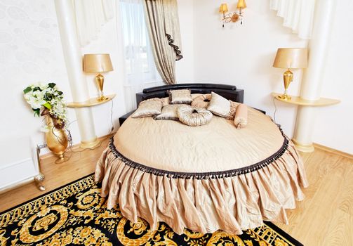 Golden classical bedroom interior with round bed and carpet