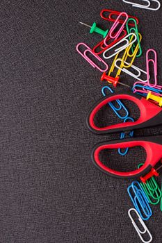 Scissors and paper clips on a black background