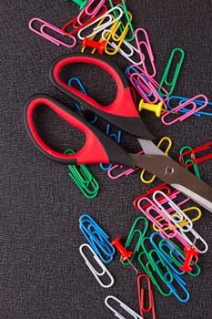Scissors and paper clips on a black background