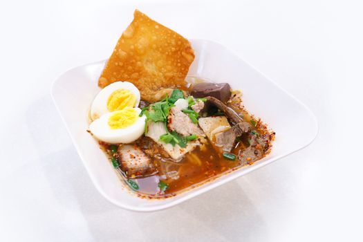 Spicy tom yum noodle with egg, pork and fried dumpling.