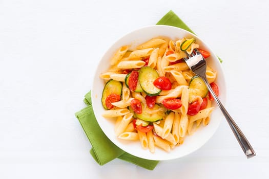 Traditional italian penne pasta with zucchini and cherry tomatoes seen from above