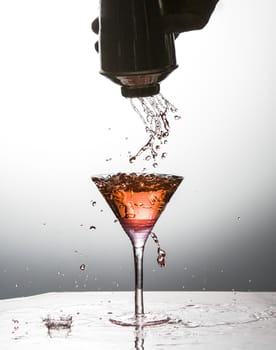 Cocktail being poured into martini glass