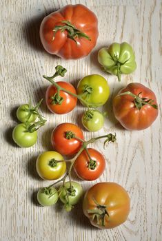 Ripe and unripe tomatoes on wooden table