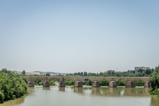 Profile side view of the Roman bridge of Cordoba on the Guadalquivir river on a bright sunny day with blue sky