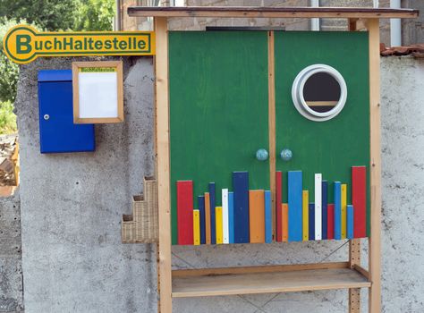 A small outdoor colorful book case and sign with german text for book stop