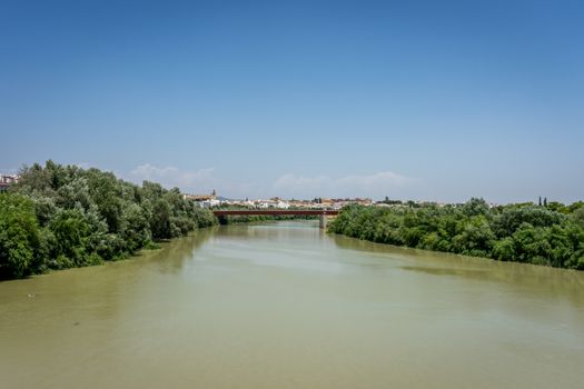 The Guadalquivir river in Cordoba, Spain, Andalucia, Europe on a bright summer day with blue sky and muddy waters