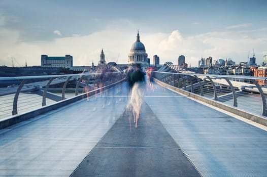 People walking over Millennium bridge at dusk.