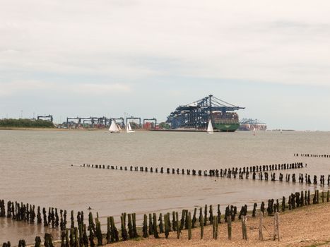 blue sea structure cranes at cargo dock loading in distance felixstowe essex beach in front