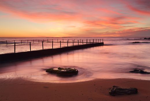 Red skies and vivid colours of dawn at Newport Beach ocean rock pool