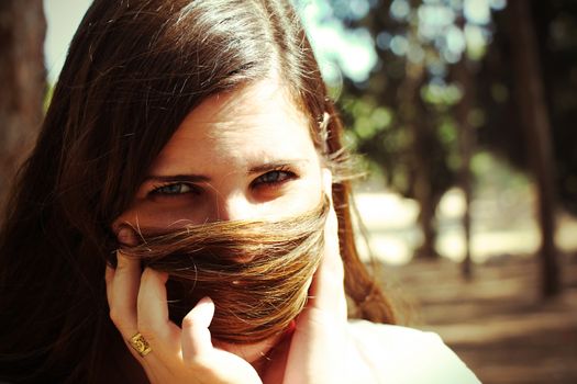 Woman hiding her face with her hair looking at camera.