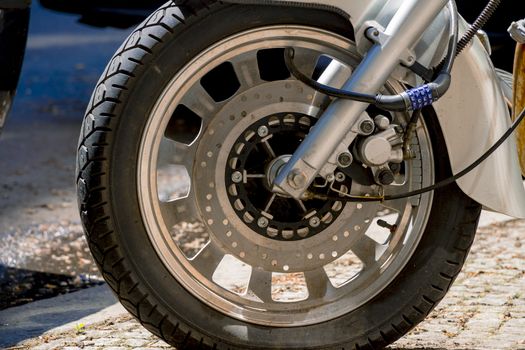 Security number padlock blocking motorcycle wheel on the street.