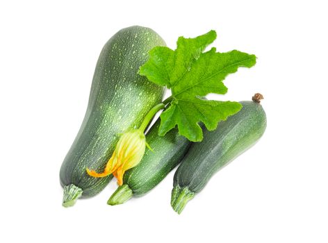 Three fresh dark green zucchini different sizes with leaf and flower on a white background
