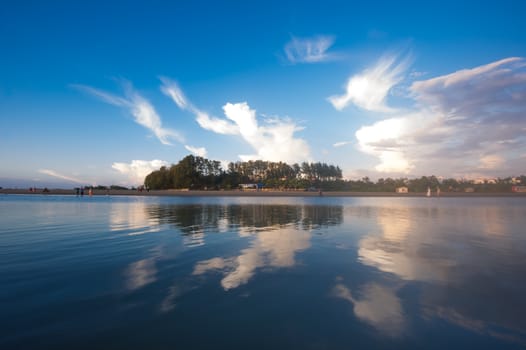 Beautiful clouds in blue sky with reflection in calm water in the morning lake. Nature wallpaper