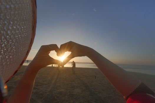 Hands make heart at sunset