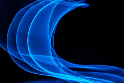 Glowing abstract curved lines.
Blue colors.
Black background.
Done by long exposure technique.