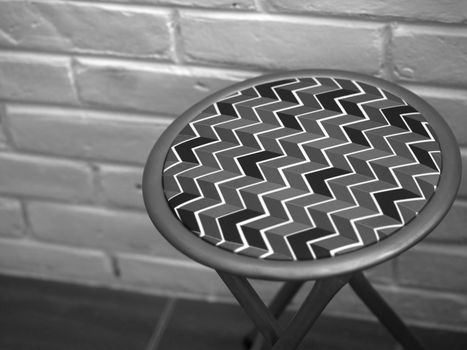 BLACK AND WHITE PHOTO OF STOOL WITH ZIG ZAG PATTERN LEATHER