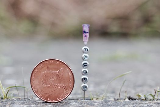 Digital currency physical brass dogecoin coin near faucet inscription on the needle.