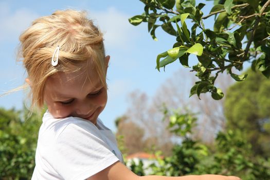 Portrait of cute baby girl posing near leafage