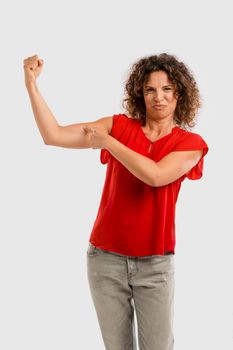 Portrait of a smiling middle aged brunette pointing to her arm muscle
