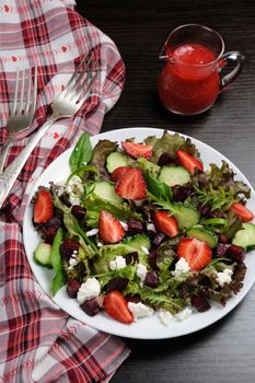 Salad of vinaigrette with strawberries, tender feta and strawberry sauce. Vertical shot.