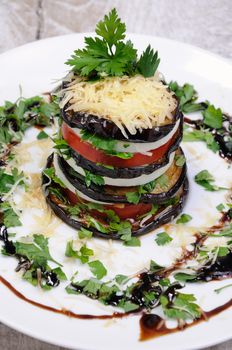 Appetizer from eggplant , slices of mozzarella combined in a pile with tomatoes spilled with herbs, seasoned   Parmesan cheese