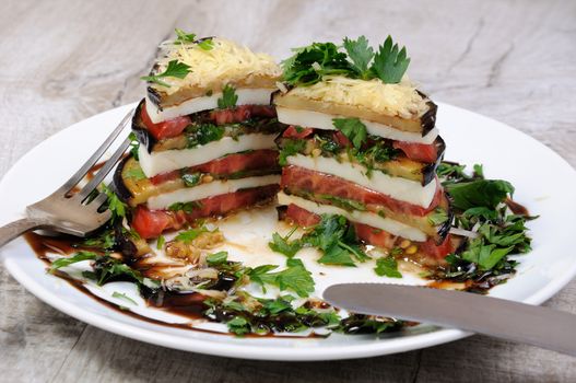 Appetizer from eggplant , slices of mozzarella combined in a pile with tomatoes spilled with herbs, seasoned   Parmesan cheese. In section