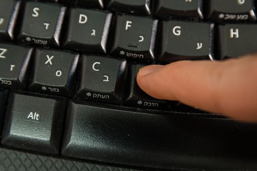 Man typing on a Wireless keyboard with letters in Hebrew and English - Press the Paste button - Top View 