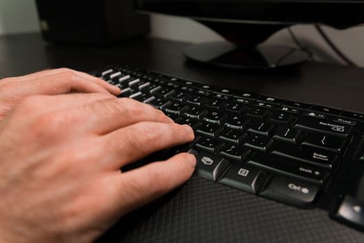 Man typing on a keyboard with letters in Hebrew and English - Wireless keyboard