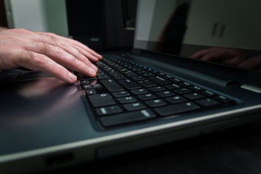 Man typing on a keyboard with letters in Hebrew and English - Laptop keyboard_Dark atmosphere