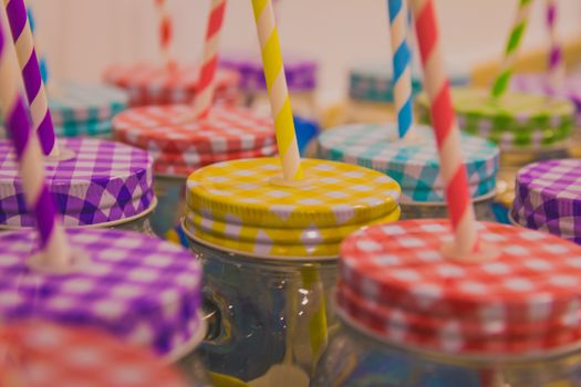 Many jars with colorful lids and drinking straws.