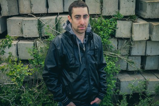 Man with serious face posing outdoor in abandoned industrial place.