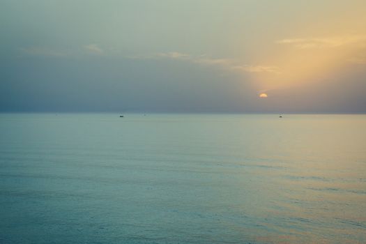 Sunset over the sea. Silhouette of boats on the horizon.