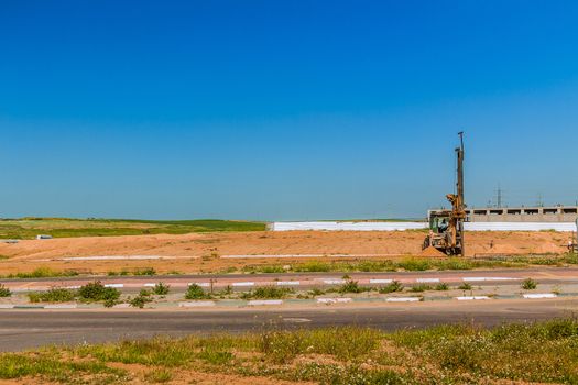 Tractor with a drilling device at a construction site.