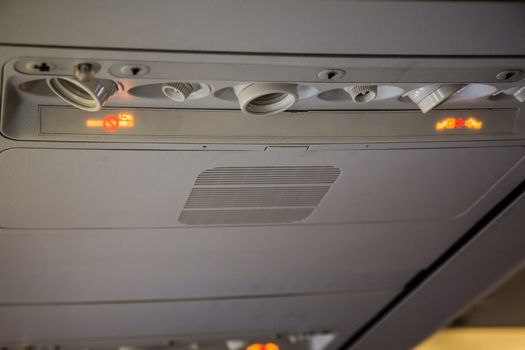 No Smoking and Fasten Seatbelt sign Inside an airplane. Overhead console in the modern passenger aircraft
