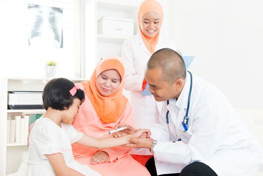 Southeast Asian doctor give injection of vaccine to children. Muslim family.