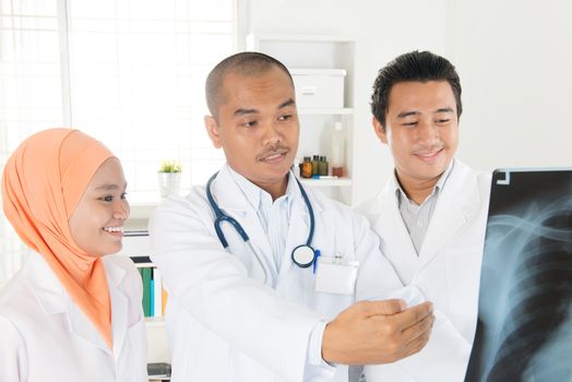 Doctors looking at x-ray scan image. Southeast Asian Muslim people.