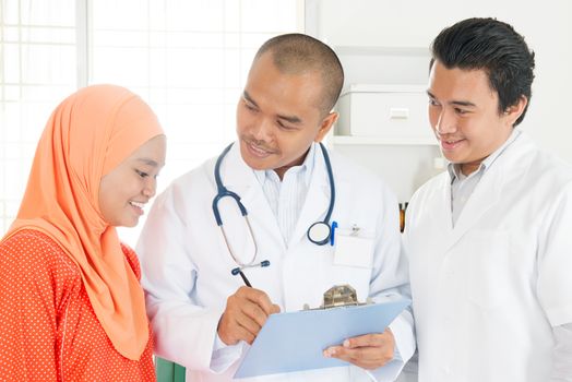 Medical team discussing treatment options with patients. Southeast Asian Muslim people.