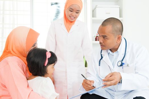 Southeast Asian pediatrician and little girl at hospital. Muslim family.