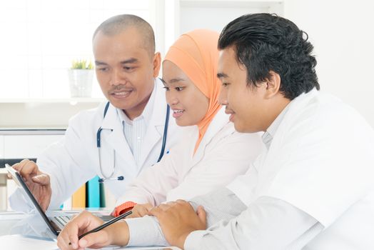 Doctors working together in the office. Southeast Asian Muslim medical people.