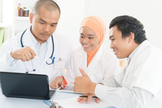 Group of doctors discuss at meeting in hospital office and showing thumb up. Southeast Asian Muslim medical people.