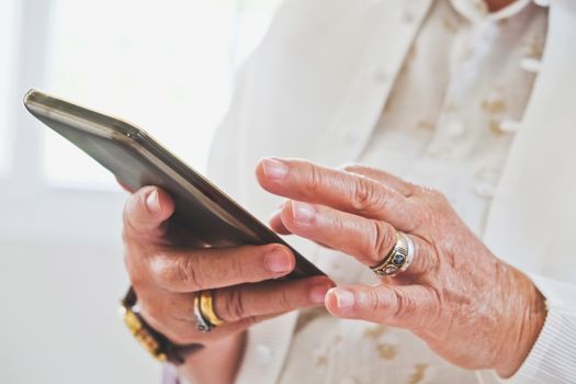close up image of Senior woman using her mobile phone background.  An idea of modern lifestyle, communication,telecommunication,connectivity, social networking