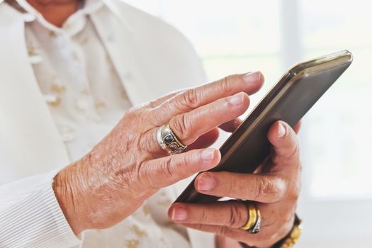 close up image of Senior woman using her mobile phone background.  An idea of modern lifestyle, communication,telecommunication,connectivity, social networking