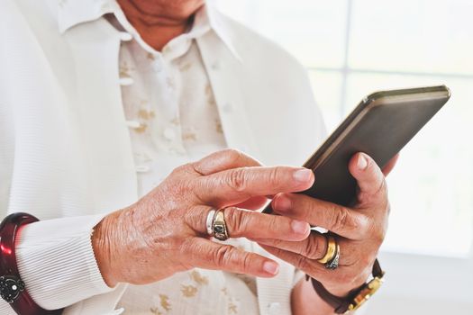 close up image of Senior woman using her mobile phone background.  An idea of modern lifestyle, communication,telecommunication,connectivity, social networking