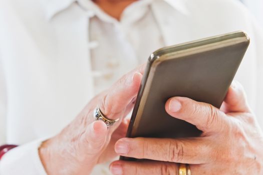 close up image of Senior woman using her mobile phone background.  An idea of modern lifestyle, communication,telecommunication,connectivity, social networking
