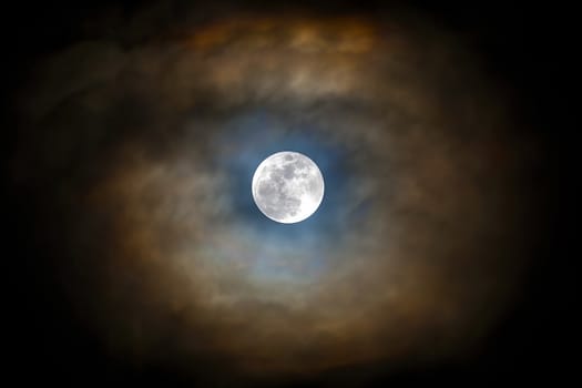 Full moon visible with parting of the clouds in the night sky