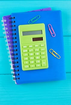 Notepad, calculator and other stationery tools on wooden table. Top view