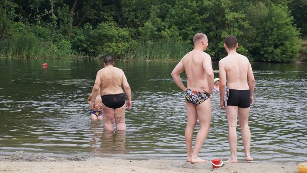 guys relax on the beach standing on the shore.