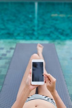 Woman use of mobile phone with swimming pool
