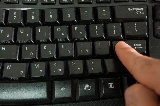 Man typing on a Wireless keyboard with letters in Hebrew and English - Press the Enter key - Top View