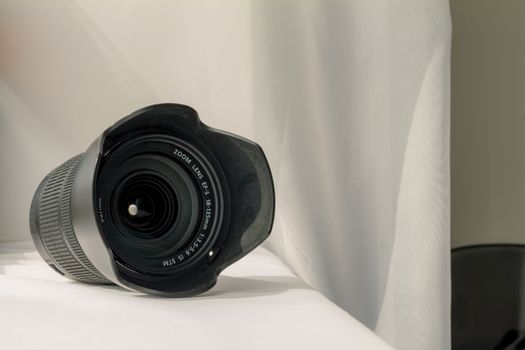 Black camera zoom lens on white cloth.